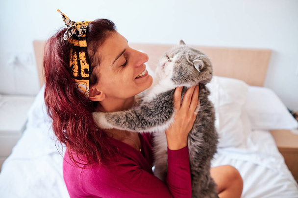 mujer feliz con su gato exótico en su dormitorio - concepto de cuidado de mascotas
 - Foto, imagen