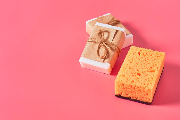 Scattered bricks of soap in vintage packing near sponge on pink background. Hygiene and cleaning concept - Photo, image