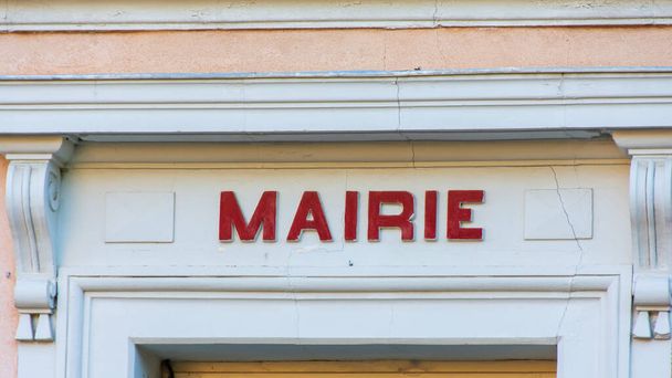 "Mairie "signo (es decir," Ayuntamiento "en francés) escrito en rojo, sobre la puerta de un ayuntamiento francés. Pequeñas grietas en la pared de la fachada
 - Foto, Imagen