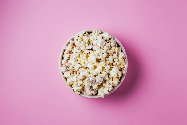 A pink bowl of popcorn on pink background, top view - Foto, afbeelding
