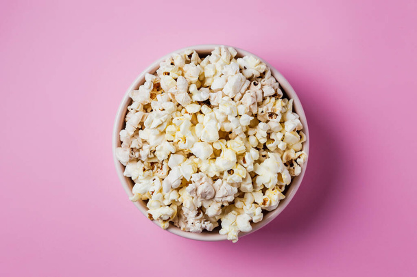 Close-up of a pink bowl of popcorn on pink background, top view - Foto, Bild