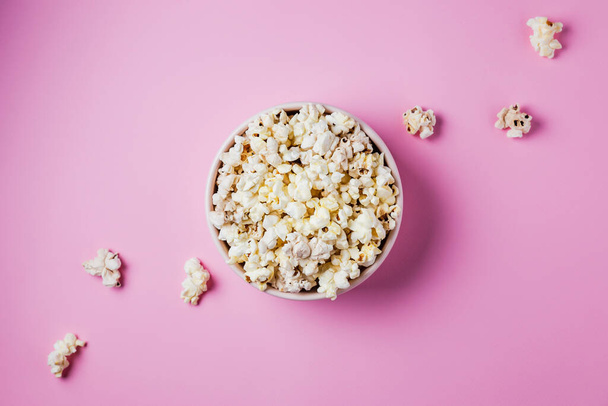 A pink bowl of popcorn on pink background, top view - Φωτογραφία, εικόνα