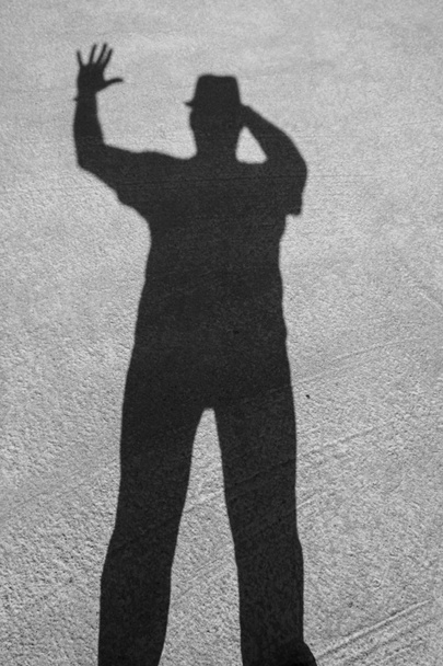 Ombra di un uomo con un cappello sul pavimento di cemento. Le mani umane mostrano simboli silhouette scura dall'ombra. Ok, cinque, ecco, vittoria. Giorno. Soleggiato. Georgia. - Foto, immagini