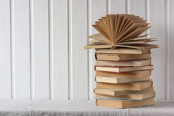 stack of old books on the table on a light background. open book.  copy space. - Фото, изображение