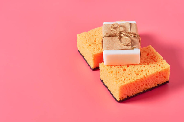 Scattered brick of soap in vintage packing near sponges on pink background. Hygiene and cleaning concept - Fotó, kép