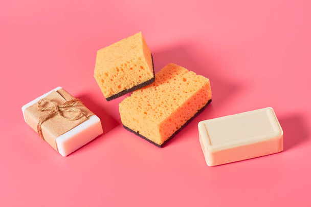 Scattered bricks of soap in vintage packing near sponges on pink background. Hygiene and cleaning concept - Fotoğraf, Görsel
