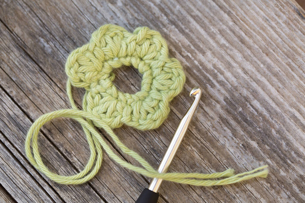 Floraison jaune au crochet avec crochet et laine sur table en bois - Photo, image