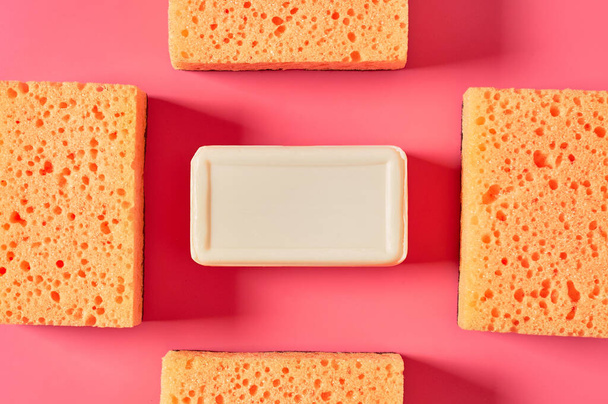 Brick of soap near sponges on pink background. Hygiene and cleaning concept - Fotografie, Obrázek