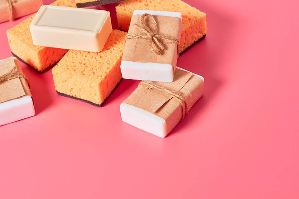Heap of bricks of soap in vintage packing and sponges on pink background. Hygiene and cleaning concept - Fotoğraf, Görsel