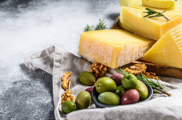 Cheese plate served with grapes, crackers, olives and nuts. Assorted delicious snacks. Gray background. Top view. Space for text. - Foto, afbeelding
