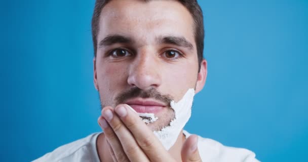Nuori mies soveltaa parranajo vaahto parta, lähikuva - Materiaali, video