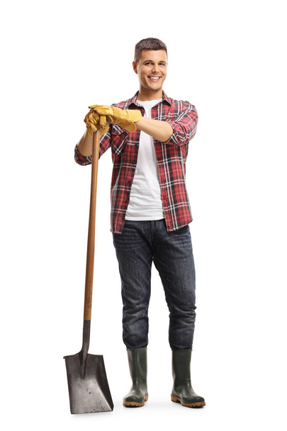 Full length portrait of a male gardener standing with a shovel isolated on white background - Fotó, kép