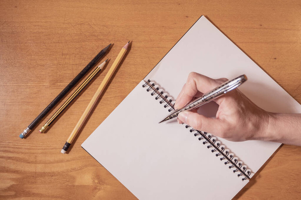 Egy üzletasszony ír egy nagy jegyzetfüzetbe egy fa asztalon. ceruzák az irodai asztalon. - Fotó, kép
