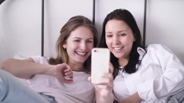 Two Young Women Taking Selfie Portrait on Phone Female Showing Positive Face Emotions Laughing Waving Hands Having Fun  - Filmati, video