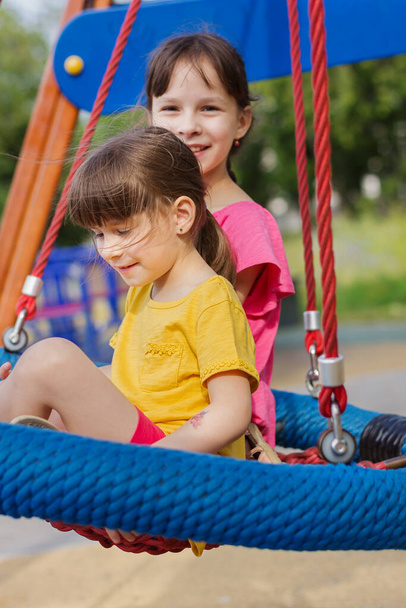 two little girls on a swing in the park - Foto, imagen
