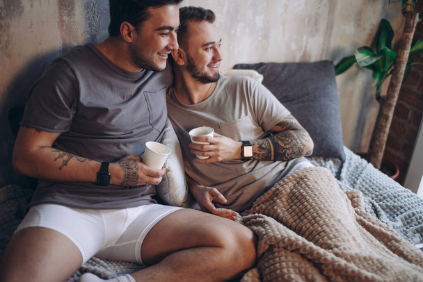 Perfect morning begins with lover and coffee in bed. Two guys resting in bed. - Foto, Bild