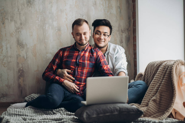 European gay male couple spend time together drinking coffee and watching laptop - Foto, immagini