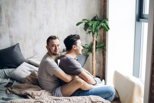 Δύο σέξι καυκάσιοι γκέι άντρες που αγκαλιάζονται και διασκεδάζουν στο κρεβάτι σε εσωτερικούς χώρους - Φωτογραφία, εικόνα