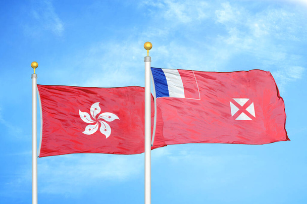 Гонконг, Уоллис и Футуна два флага на флагштоках и голубом облачном фоне неба - Фото, изображение