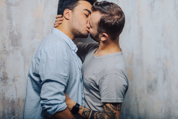 Cay couple enjoy togetherness indoors, kiss each other - Fotó, kép