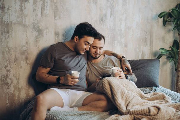 Perfect morning begins with lover and coffee in bed. Two guys resting in bed. - Foto, afbeelding