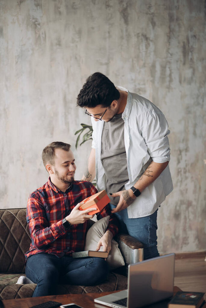 Happy surprised young handsome gay couple celebrating and giving gift at home - Foto, Bild