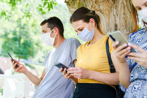 Side view of caucasian man and women use mobile phones - Modern communication online texting social network message - Group of people with mask hold mobile phones - social distance new normal concept - Fotó, kép