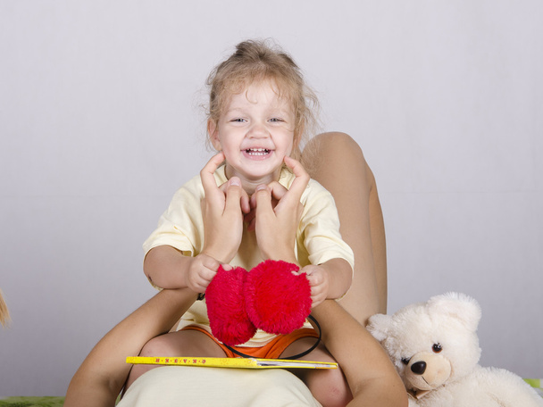 Маленька дівчинка сидить на мамі і сміється
 - Фото, зображення
