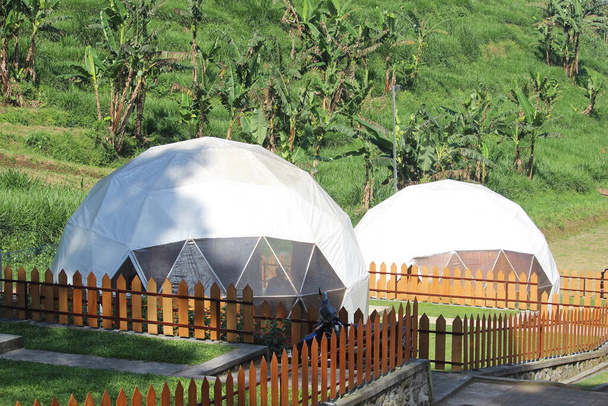 丸みを帯びた白いテントはインドネシアで最も美しい自然の中でグラマーキャンプと名付けられました - 写真・画像