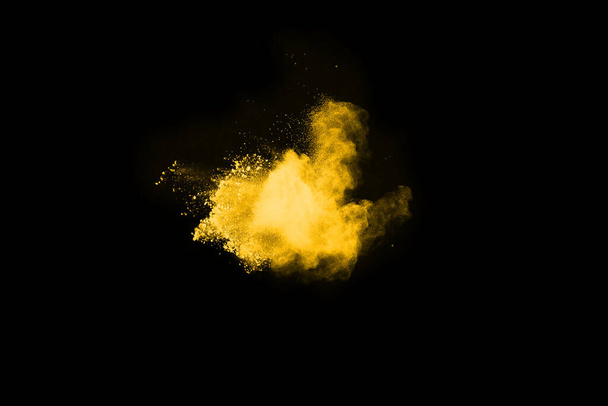 Congelar el movimiento de la explosión de polvo amarillo aislado sobre fondo negro. - Foto, imagen
