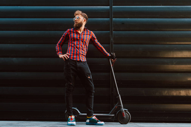 Şehirde elektrikli scooter kullanan yakışıklı bir adam. - Fotoğraf, Görsel