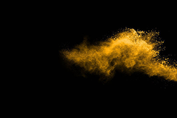 Bevries beweging van gele stof explosie geïsoleerd op zwarte achtergrond. - Foto, afbeelding
