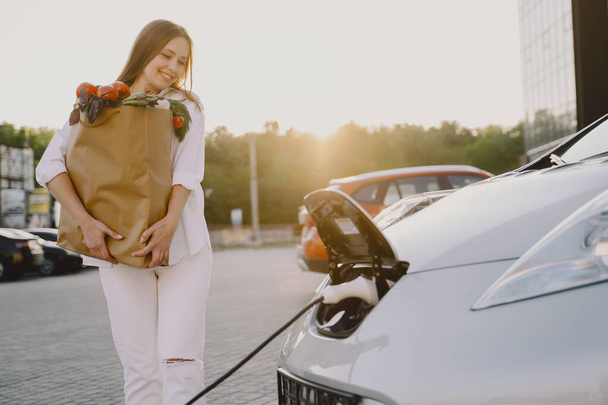 Woman charging electro car at the electric gas station - Fotó, kép