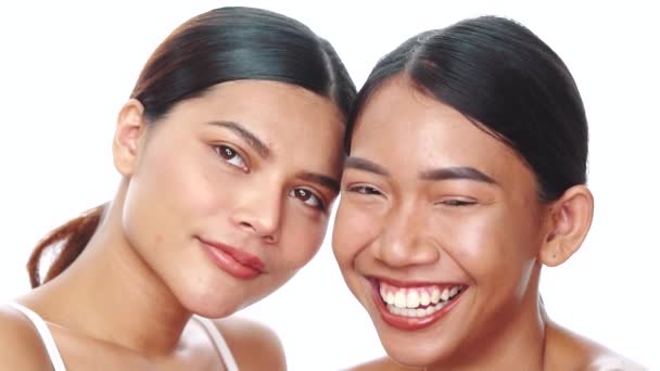İki güzel Asyalı kadının beyaz arka plandan kameraya bakıp gülümsediği yakın çekim yüzleri. Doğal güzellik. Cilt bakımı kozmetikleri - Video, Çekim