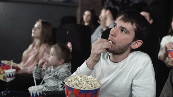 Dolly move van mensen eten popcorn en kijken naar een film in de bioscoop - Foto, afbeelding