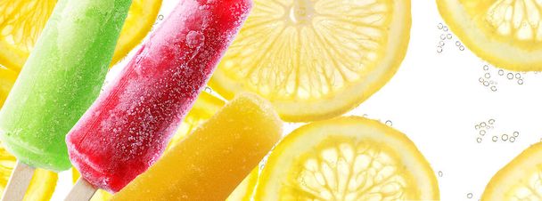Яскраві палички на шматочках лимона на фоні содової води
 - Фото, зображення