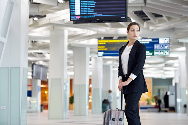 Young asian business woman at the airport with trolley bag, waiting for departure. - Фото, изображение