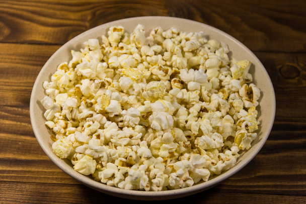 Bowl with popcorn on wooden table - Photo, Image