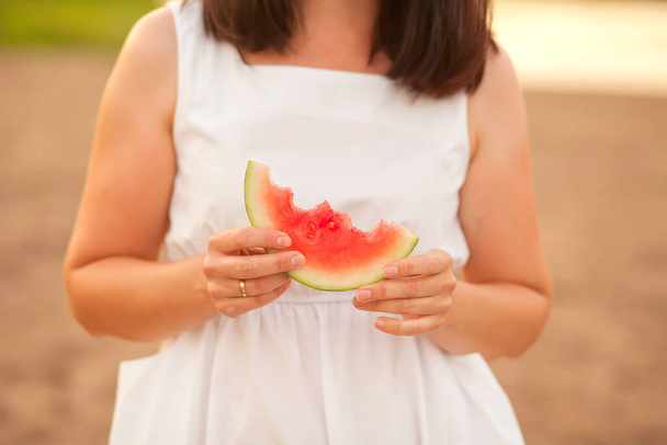 Woman with a piece of ripe watermelon in a hand in a picnic. Summer picnic. Vacation concept - Foto, Imagen