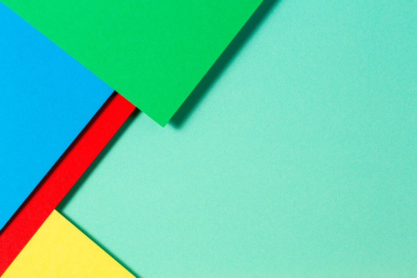 Abstraktní barevné papíry geometrie byt ležel složení pozadí s modrými, žlutými, červenými a zelenými tóny - Fotografie, Obrázek