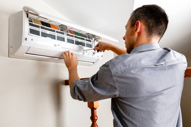 Male technician cleaning air conditioner indoors - Photo, image