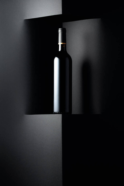 Ongeopende fles rode wijn op een zwarte achtergrond. Kopieer ruimte voor uw tekst. - Foto, afbeelding
