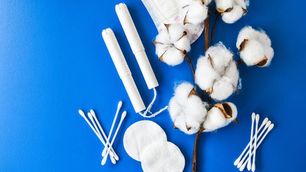 All made of cotton. Hygiene accessories - sanitary napkins, cotton pads, cotton swabs, tampons on blue background. Concept of critical days, menstruation. Zero waste eco-friendly. Top view. Copy space - Photo, Image