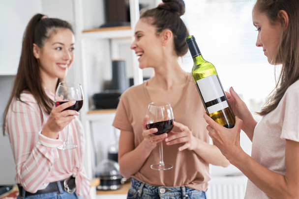 Trois femmes boivent du vin rouge à la maison - Photo, image