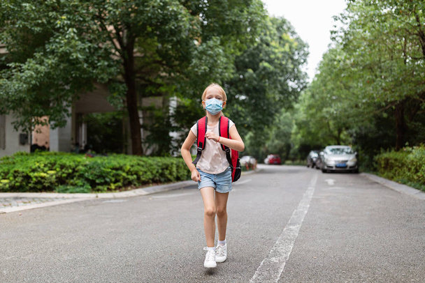 School child after end coronavirus pandemic outbreak. Blonde girl going back to school after covid-19 quarantine and lockdown. Happy kid outdoor. New normal. High quality photo - Foto, Bild