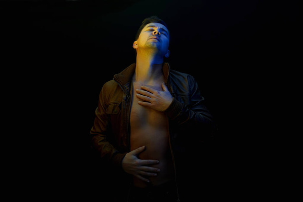 young Man. sexy Handsome Boy in color lights. Male model posing in black studio - Photo, Image