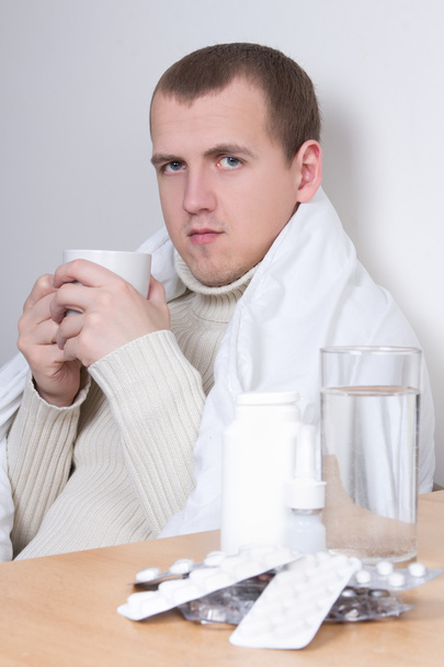 хворий чоловік п'є чай у вітальні
 - Фото, зображення