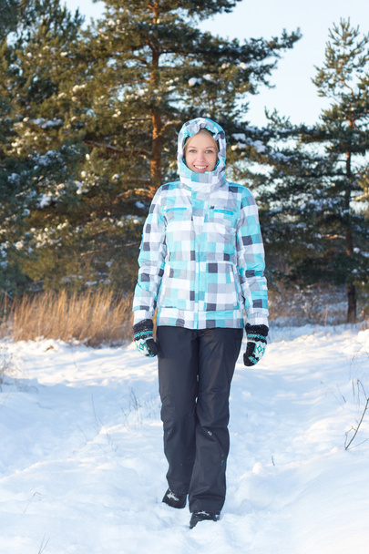 kobieta w Błękitnej Kurtki kratkę spaceru w lesie zimą - Zdjęcie, obraz