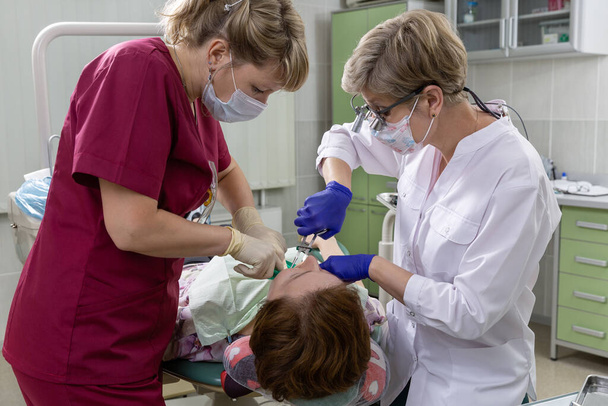 Doctor and nurse in the dental office. The patient receives treatment. - 写真・画像