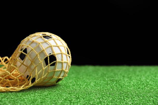 Μπάλα ποδοσφαίρου στο πράσινο πεδίο σε σκούρο φόντο - Φωτογραφία, εικόνα
